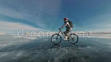 女人在冰上骑自行车。 女孩穿着银色羽绒服，自行车背包和头盔。 冰冰